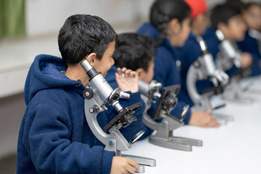 Students using microscopes in a science classroom, representing education finance supporting school fees and access to quality learning opportunities.